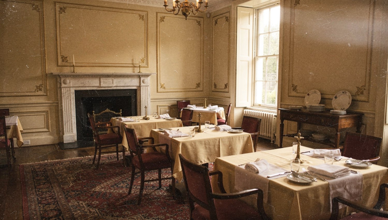 The Ivory Dining Room — set tables, ivory linen, brass candlesticks, sash windows